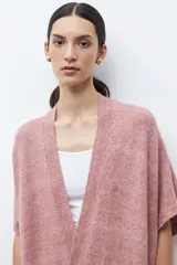 Ruana de tejido de punto color rosa melange, sin mangas y con cuello redondo.