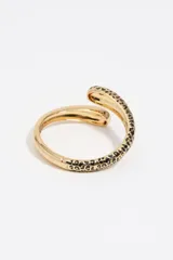 Pulsera rígida dorada con diseño de manchas de leopardo en uno de sus extremos. Presenta un cierre de bisagra y está confeccionada principalmente en latón con detalles de esmalte y acero inoxidable.