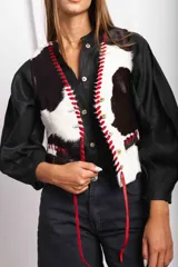 Chaleco con estampado de vaca en tonos marrones y blancos, con detalles de pasamanería en cuero.