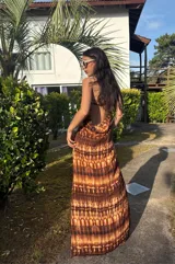 Vestido strapless largo con estampado batik en tonos marrones y beige, entallado al cuerpo y con espalda baja descubierta.