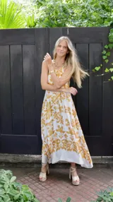 Vestido largo de seda con estampado de flores en color blanco y amarillo, con corte halter.