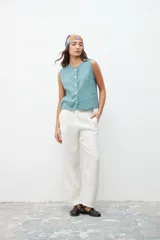 Chaleco color celeste con textura, corte recto, sin mangas y abotonado al frente.