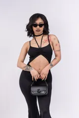 Mono enterizo negro ajustado al cuerpo, con escote halter y abertura en el abdomen.