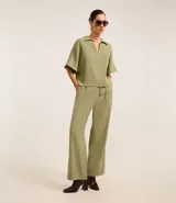 Blusa verde oliva de mangas cortas amplias, confeccionada en viscosa, con cuello y recortes verticales en los laterales.