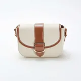 Bolso bandolera de lona color beige con detalles en cuero marrón. Tiene correa larga ajustable y cierre con hebilla dorada.