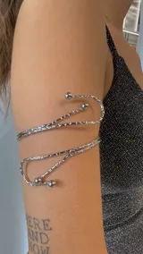 Brazalete plateado con diseño de espiral y terminaciones con bolitas.