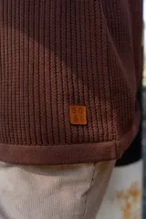 Remera tejida color crudo con cuello redondo con borde verde, mangas cortas y bolsillo en el pecho. Corte holgado.