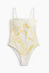Traje de baño enterizo con estampado de hojas en tonos amarillo y blanco, breteles finos y escote recto.