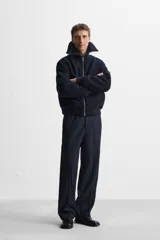 Pantalón de vestir azul marino, de corte recto, con bolsillos laterales y traseros. Incluye un bolsillo tipo cargo en la pierna izquierda. Se ajusta a la cintura con cinturón de cuero marrón.