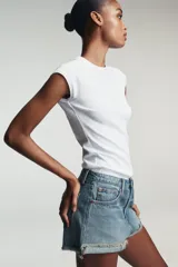 Shorts de jean de algodón, tiro alto, color azul claro desgastado. Presenta cinco bolsillos, cierre frontal con botón metálico y bajo desflecado con vuelta.