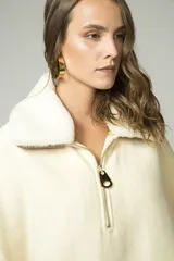 Poncho color crema con cuello de corderito desmontable y cierre dorado.