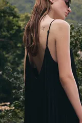 Mono de mujer color marrón oscuro, con escote redondo y tirantes finos. El tejido es satinado y plisado verticalmente. El pantalón es estilo bombacho con bajo abullonado ajustado con botón.