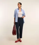 Pantalón de vestir azul marino, de corte zanahoria, con cinturón fino negro con hebilla dorada.