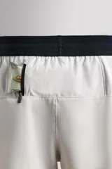 Shorts deportivos color verde oliva confeccionados en tejido técnico ligero y elástico. Cuenta con forro interior, cintura elástica ajustable con cordón, bolsillos laterales, bolsillo de seguridad en espalda con cierre de cremallera, bajo con aberturas laterales y logo estampado en la pierna.