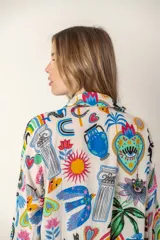 Camisa larga de color blanco con estampado de flores azules, cuello en V y mangas largas.