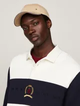Gorra de béisbol clásica de seis paneles color beige, confeccionada en algodón. Presenta un pequeño logo rectangular de Tommy Hilfiger en la parte delantera y ribetes con los colores distintivos de la marca en el borde de la visera.