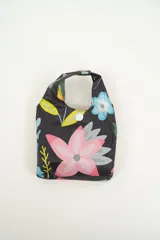 Tote bag de tela con estampado de hojas de palmera en tonos azul, celeste y rosa. Tiene doble asa superior y cierre con botón a presión.