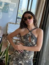 Vestido corto de lentejuelas color verde oliva, con escote en V, breteles finos cruzados en la espalda, cut-outs laterales y volado en el ruedo.