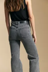 Jean de corte recto y tiro medio, color gris oscuro con efecto lavado. Presenta apliques de tachas metálicas pequeñas en la zona de los bolsillos delanteros.