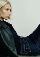 Bolso bandolera de cuero color marrón oscuro, con correa ajustable y cierre superior con cremallera.