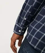 Camisa de franela a cuadros color negro, con botones blancos y mangas largas.