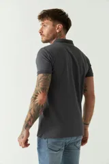 Remera polo negra de manga corta con cuello clásico, cierre de botones, bolsillo en el pecho y logo estampado.