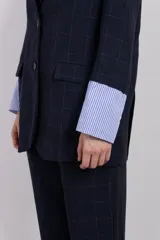 Blazer azul marino a cuadros con solapas de muesca, cierre con dos botones, dos bolsillos delanteros con solapa y un bolsillo en el pecho.