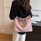 Bolso tipo tote color celeste con correa larga verde y asas cortas.