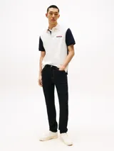 Chomba Tommy Hilfiger de hombre con diseño color block en blanco y azul marino. Tiene cuello tipo chomba, cartera de dos botones y logo bordado en el pecho.