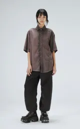 Camisa manga corta color gris con efecto desgastado, corte holgado y cierre frontal con botones.