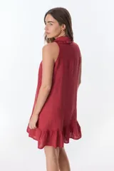 Vestido corto color ladrillo, sin mangas, con cuello camisero con volados, abotonado al frente y falda con volados.