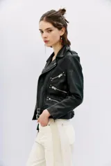 Campera de cuero ovino negra, estilo rocker, con cuello con solapas, cierre cruzado, cinturón ajustable en la cintura, charreteras en los hombros y múltiples cierres metálicos decorativos. Forro de poliéster.