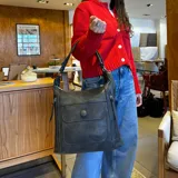 Cartera negra de símil cuero con doble cierre superior, bolsillo frontal con tapa y broche magnético, bolsillos laterales con cierre y correa larga regulable y desmontable.