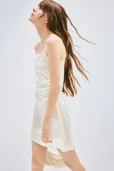 Vestido corto de breteles finos color blanco, con escote recto y frunces laterales que generan un efecto drapeado.