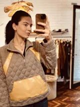 Sweater blanco con diseño acolchado, cierre parcial con cremallera, detalles en cuero color marrón y bolsillo tipo parche en el frente.