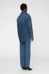 Camisa vaquera de denim azul con lavado mosaico, corte recto, cuello camisero, cierre frontal con botones a presión, mangas largas con puños abotonados, dos bolsillos de parche en el pecho y bajo redondeado. Marca Anine Bing.
