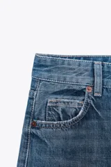 Pantalón de jean rígido celeste con tiro alto, cinco bolsillos, trabillas en la cintura, pierna ancha y largo hasta el tobillo.