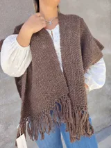 Ruana tejida color marrón con flecos en el ruedo.