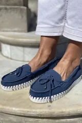 Mocasín náutico dorado de cuero con detalle de lazo en la parte delantera y suela de goma color caramelo.