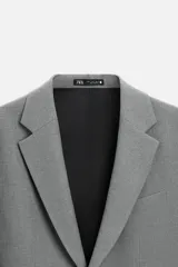 Blazer straight fit color gris claro confeccionado en tejido con viscosa. Tiene cuello con solapas de muesca, manga larga acabada en puño con botón, bolsillo de vivo en pecho, bolsillos de plastrón en cadera y bajo con aberturas en espalda. Cierre frontal de botonadura.