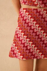 Minifalda de tejido de punto con estampado geométrico en tonos rojo, rosa, naranja y blanco.