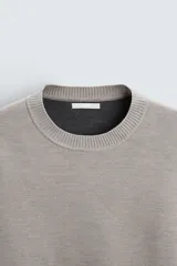Sweater negro de punto con cuello redondo y mangas largas.