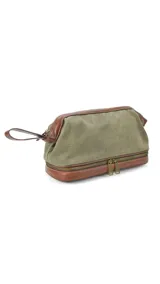 Neceser verde de tela canvas combinado con símil cuero marrón. Tiene apertura superior con cierre metálico estructural, doble bolsillo interno (uno con cierre y otro abierto con división) y base con cierre que actúa como bolsillo extra.