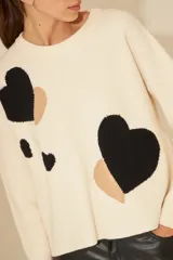 Sweater de punto con diseño de manchas en color beige y burdeos, con corte holgado y mangas largas.