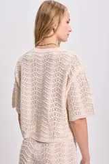 Top de punto calado color crudo con cuello redondo y mangas cortas.