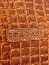 Bandolera de cuero marrón con diseño texturizado y detalles blancos, con interior forrado y dos bolsillos.