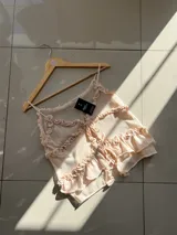 Blusa color crema con tirantes finos, escote en V y volados.