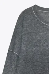 Sweater gris de punto con cuello redondo y manga larga. Detalle de costuras a contraste en color blanco en cuello y hombros.