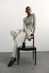 Pantalón de vestir color beige, de corte ancho y tiro alto, con pinzas delanteras, bolsillos laterales y cierre frontal.