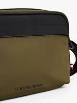 Bandolera Tommy Hilfiger color verde militar con detalles en negro y correa ajustable con la bandera de la marca. Incluye logo metálico en el frente y cierre de cremallera.